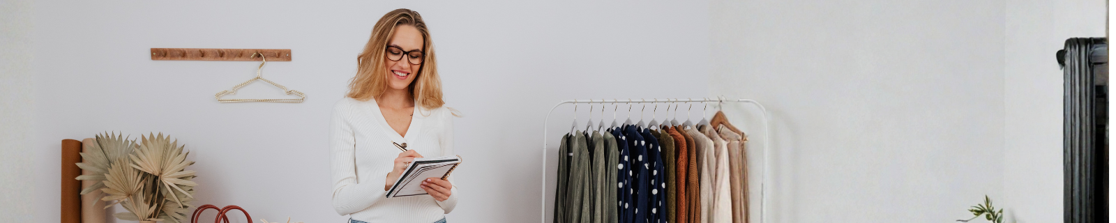 women standing next to a clothing rack holding a notepad and pen
