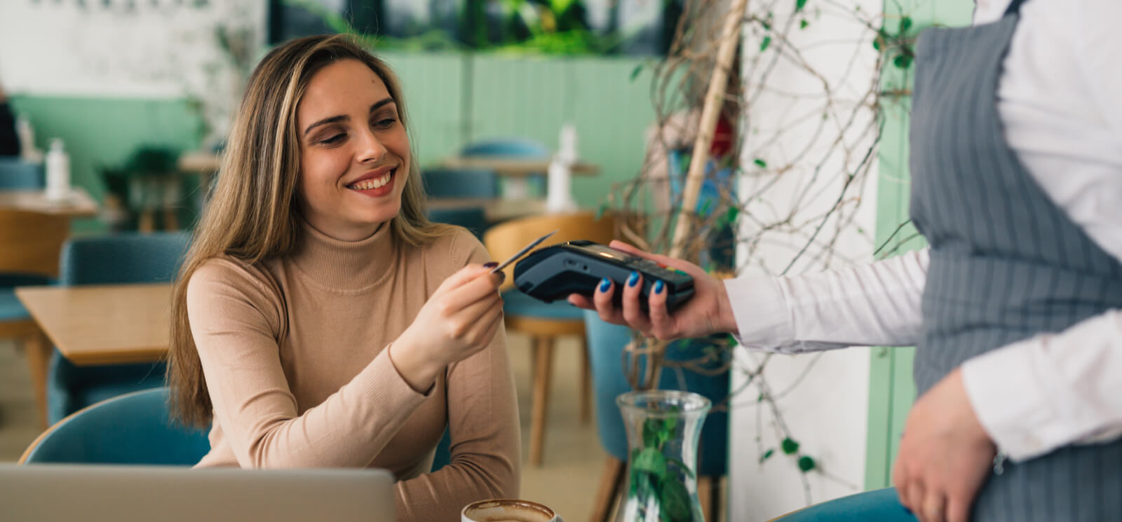 A young woman paying in a cafe with a credit card